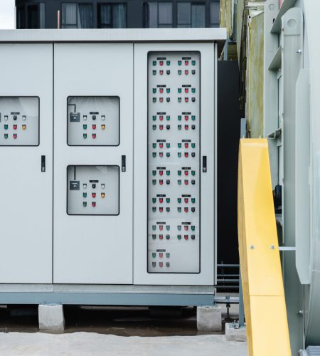 The electrical room of a commercial building contains multiple smart meters, a main power breaker, and various meter stacks and cabinets.